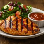 A close-up of a plate featuring Chick-fil-A-style grilled chicken served with a fresh salad and dipping sauce on a rustic table, highlighting the recipe's vibrant and delicious appeal.