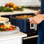 "A Ninja Air Fryer on a kitchen counter being used to cook a meal, with a plate of roasted vegetables and colorful ingredients in the foreground.